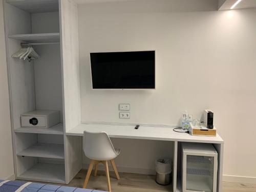 a white desk with a chair and a television on a wall at Nerja Casual Rooms in Nerja