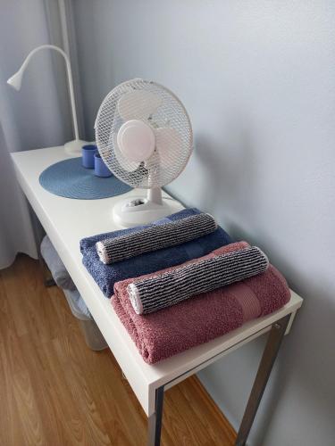 a small white table with a fan and towels at Citykoti in Varkaus