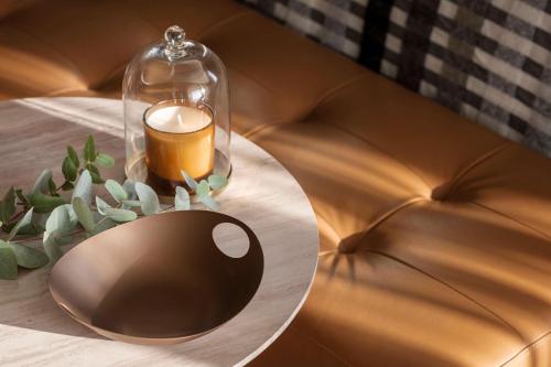 a table with a candle and a glass jar on a couch at One&Only Portonovi in Herceg-Novi