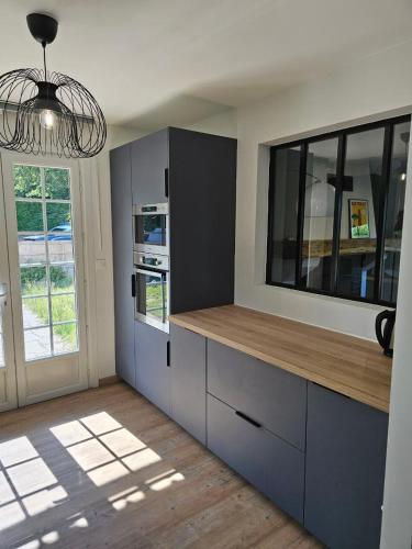 une cuisine avec des placards bleus et une grande fenêtre dans l'établissement Villa 47, à Lège-Cap-Ferret