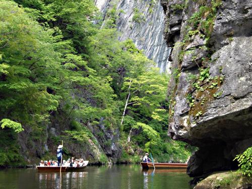 un groupe de personnes dans un bateau sur une rivière dans l'établissement Kajiyabekkan Ramakkoro Yamaneko Yado, à Ichinoseki