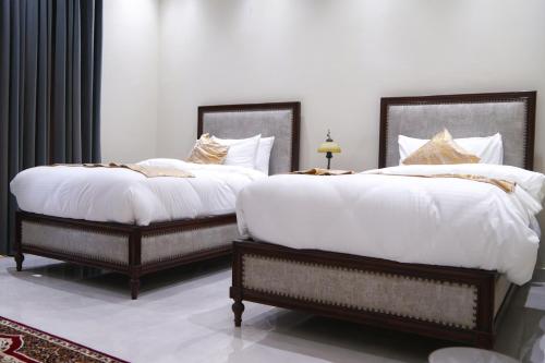 two beds with white sheets and pillows in a bedroom at Hidden Hills Hotel & Resort in Mānsehra