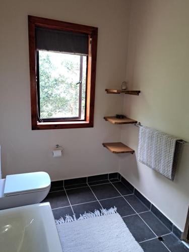 a bathroom with a toilet and a window at "The Gatehouse", Goosebumps - Cottage in Lake Brenton on Knysna Lagoon in Brenton-on-Sea
