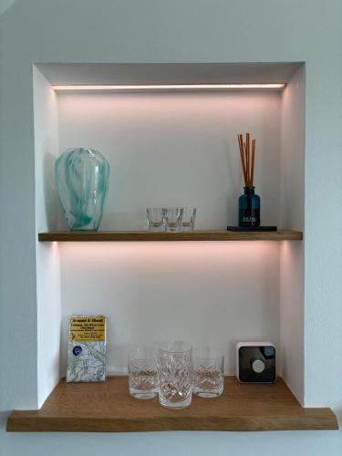 a shelf with glasses and a clock on it at Cannister Hall Apartment, Selling, Faversham, Kent in Faversham