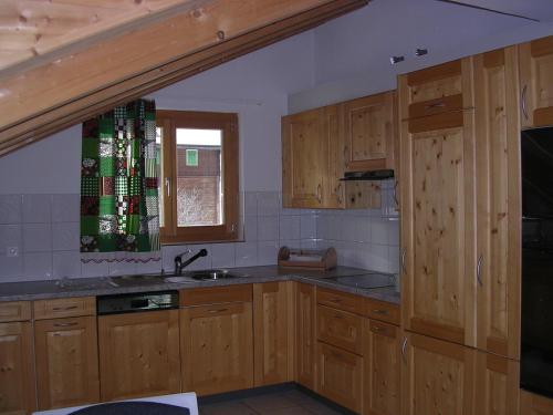 eine Küche mit Holzschränken, einem Waschbecken und einem Fenster in der Unterkunft Gotschnablick in Klosters