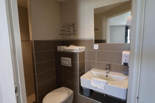 a bathroom with a sink and a toilet and a mirror at Brit Hotel Montpellier Eurom&eacute;decine in Montpellier