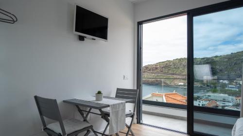 a dining room with a table and a large window at V&J Guest Suite in Machico