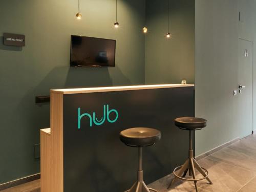 a counter with two stools and a tv on a wall at HUB Rooms in Carini