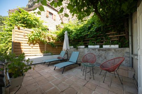 a patio with a table and chairs and an umbrella at Logis Hôtels - Hôtel Restaurant Domaine Les Falaises in Martel