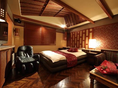 a bedroom with a bed and a chair in it at Hotel La Siesta (Adult Only) in Kyoto