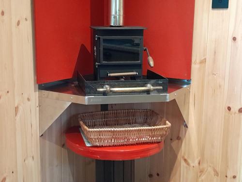 a counter with a stove and a basket on a stool at Little Greenwood Shepherd Hut in Boughton Malherbe