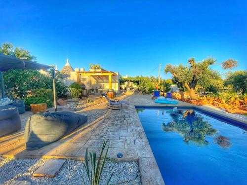 a pool at a resort with trees and a building at Trullideserio in San Michele Salentino