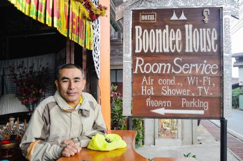 a man sitting at a table in front of a sign at Boondee House in Mae Hong Son