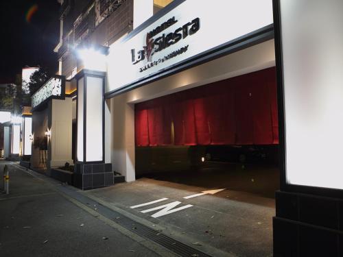 a store with red curtains on a street at night at Hotel La Siesta (Adult Only) in Kyoto
