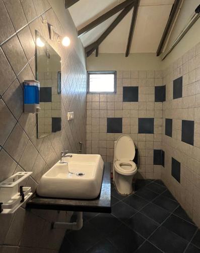 a bathroom with a white toilet and a sink at The Village Resort in Kodāe