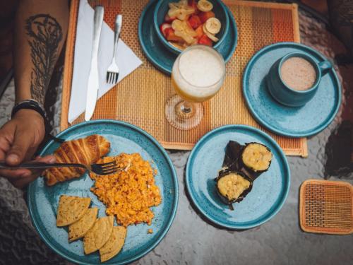 a table with plates of breakfast food and a person holding a fork at Casa Raisol Barichara in Barichara