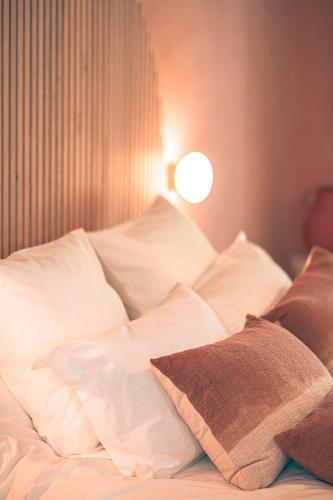 a bed with white sheets and pillows in a room at Les Suites de l'Étang in Cucuron