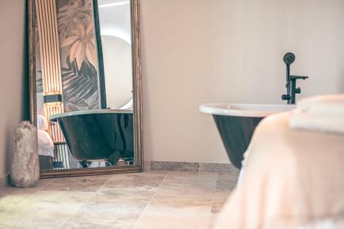 a bathroom with a bath tub and a mirror at Les Suites de l'Étang in Cucuron
