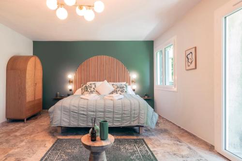 a bedroom with a bed and a green wall at Les Suites de l'Étang in Cucuron