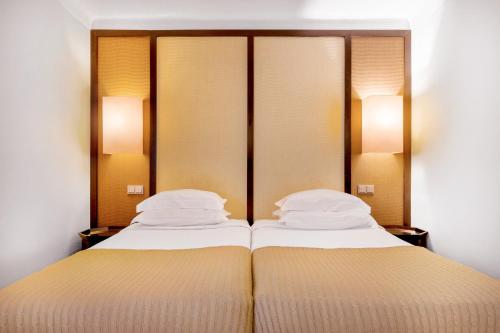 two beds in a hotel room with two lamps at Pousada Forte da Horta in Horta