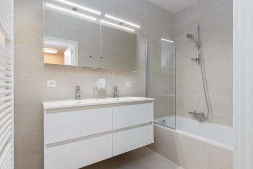a white bathroom with a sink and a shower at Sky Bridge Ostend - Casselbergh Residences in Ostend
