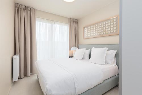 a bedroom with a large white bed and a window at Sky Bridge Ostend - Casselbergh Residences in Ostend