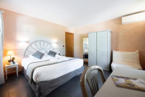 a hotel room with a large bed and a table at Logis Hôtels - Hôtel Restaurant Domaine Les Falaises in Martel