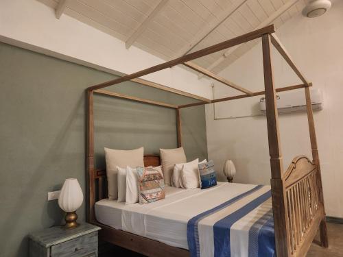 a bedroom with a canopy bed with white pillows at Nagenahira Beach Villa in Nilaveli