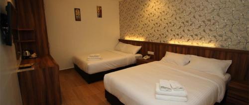 a hotel room with two beds with white sheets at Century Inn Hotel in Cukai