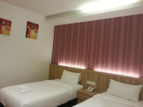 two beds in a hotel room with pink walls at Century Inn Hotel in Cukai