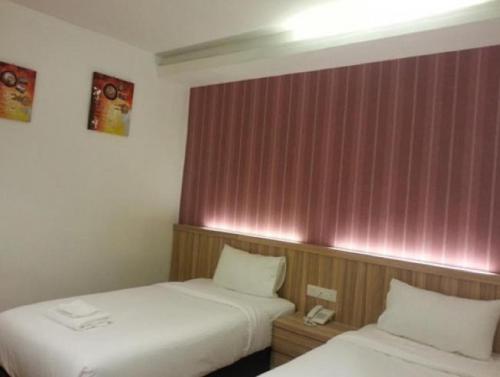 two beds in a hotel room with pink walls at Century Inn Hotel in Cukai