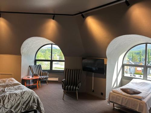 a bedroom with two chairs and a bed and two windows at Grong Hotell in Grong