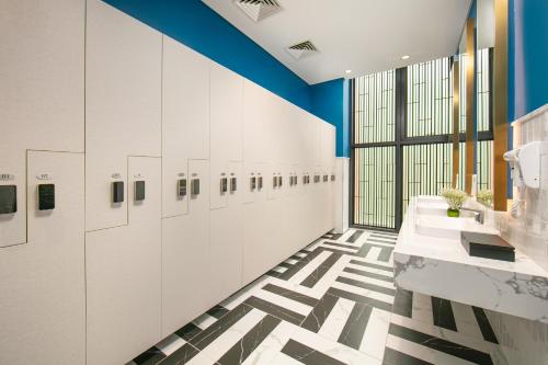 a bathroom with white and blue walls and a checkered floor at Mövenpick Living West Hanoi in Hanoi