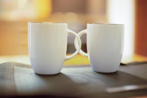 two white coffee mugs sitting on top of a table at Seelina in Perach