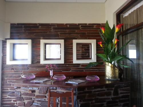 a room with a brick wall and a table with flowers at The Homestead Margate - South Africa in Margate
