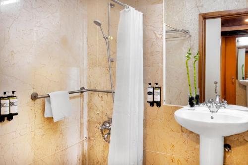 a bathroom with a sink and a shower with a white shower curtain at Pousada Forte da Horta in Horta
