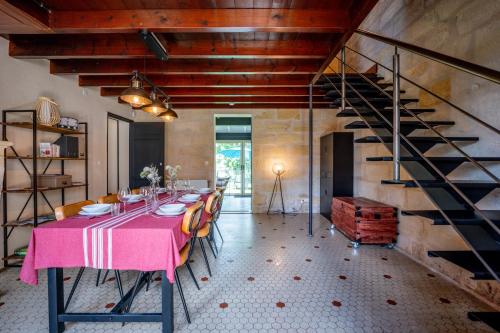 a dining room with a pink table and a staircase at L'Annexe Mauvilla in Civrac-de-Dordogne
