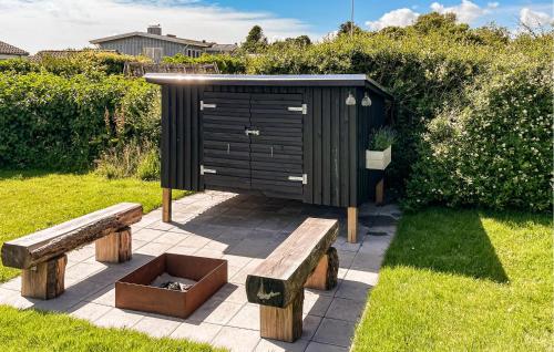 a black shed with two benches in a yard at Awesome Home In Øster Assels With Sauna in Øster Assels
