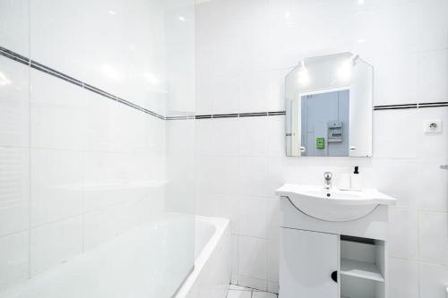 une salle de bain blanche avec un lavabo et un miroir dans l'établissement Appartement Plein Pied cœur de Neuilly-sur-seine, à Neuilly-sur-Seine