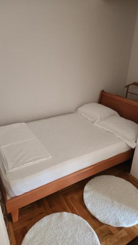 a bed with white sheets and two rugs in a room at Sky Center Apartment in Podgorica