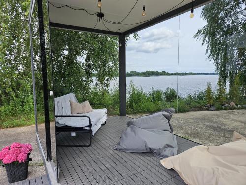 a screened porch with a chair and a view of the water at Pamesta kuģu piestātne in Katlakalns
