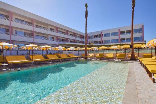 a pool with chairs and umbrellas in front of a hotel at Los Felices Ibiza in San Antonio Bay