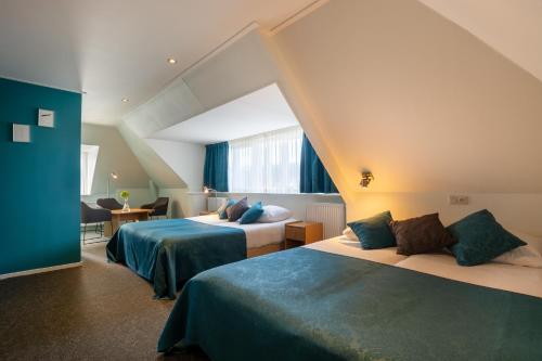 a hotel room with two beds and a window at Hotel Oepkes in West-Terschelling