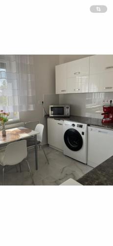 a kitchen with a washing machine and a table at Aranyapartman in Kisbajcs