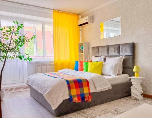 a bedroom with a large bed with colorful pillows at 12 Microragion Apartments in Aktobe
