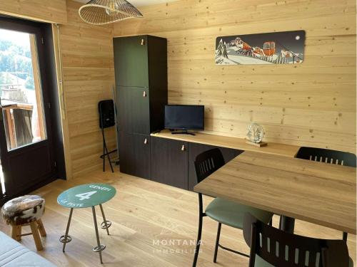 Cette chambre est dotée d'un mur en bois avec une table et des chaises. dans l'établissement Studio rénové pour 4 au Grand-Bornand, balcon, casier à ski - FR-1-458-194, au Grand-Bornand