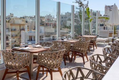 a row of tables and chairs on a balcony with windows at Ethereal White Resort Hotel & Spa - Adults Only in Heraklio Town