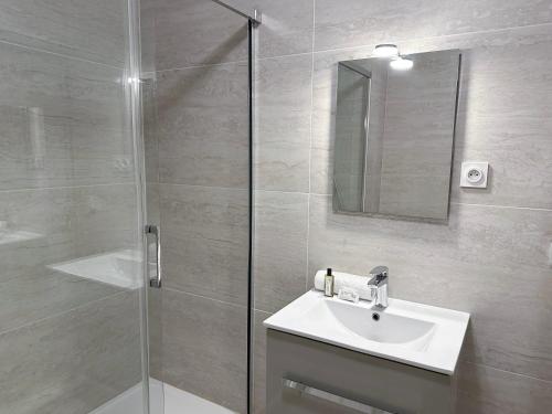 a bathroom with a sink and a glass shower at Brand-new studio with Eiffel Tower view in Paris