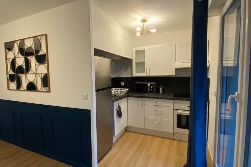 - une cuisine avec des armoires blanches et des placards noirs et blancs dans l'établissement T2 refait à neuf Lille ! Parc Monceau, à Lille