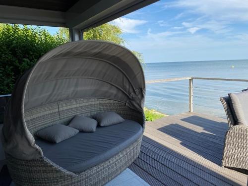 a wicker chair sitting on a deck with the ocean at Seaside in Bovenkarspel